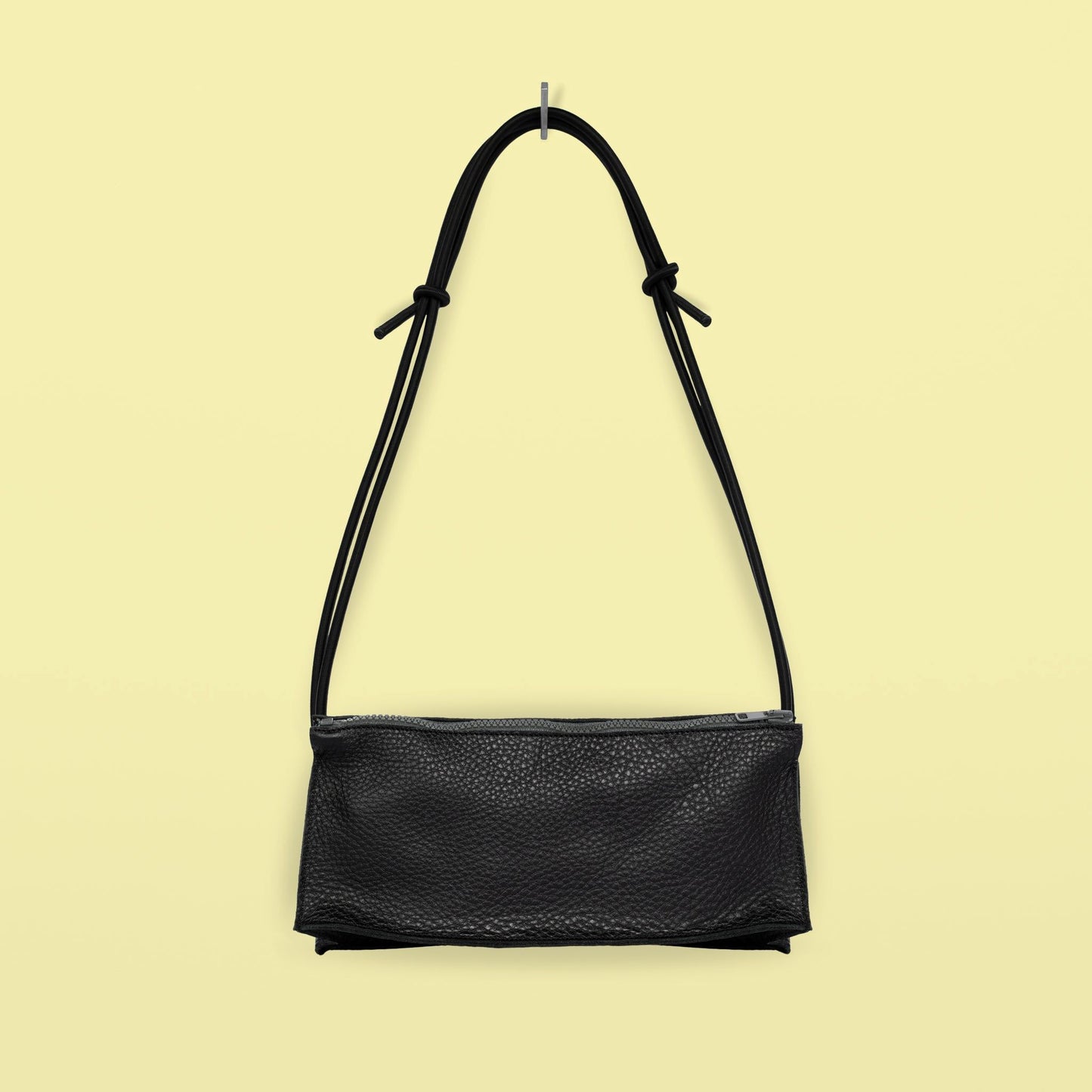 Daz Studion käsintehty crossbody-laukku, joka on valmistettu mustasta aidosta nahasta. Musta olkahihna on säädettävä ja elastinen.