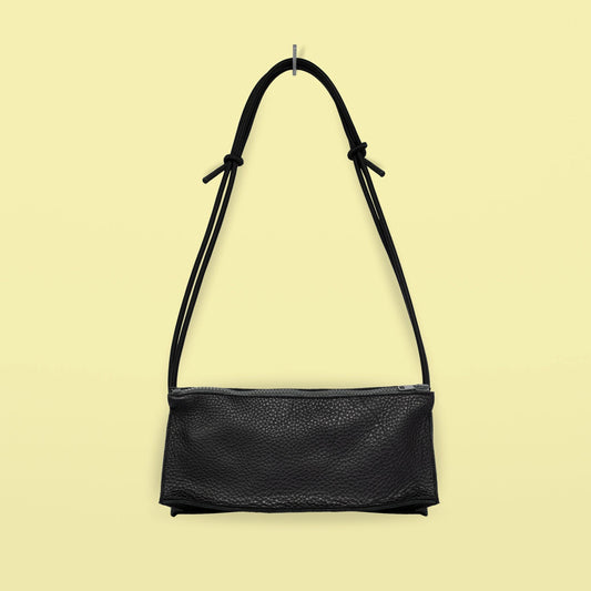 Daz Studion käsintehty crossbody-laukku, joka on valmistettu mustasta aidosta nahasta. Musta olkahihna on säädettävä ja elastinen.