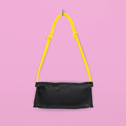 Daz Studion käsintehty crossbody-laukku, joka on valmistettu mustasta aidosta nahasta. Keltainen olkahihna säädettävä ja elastinen.