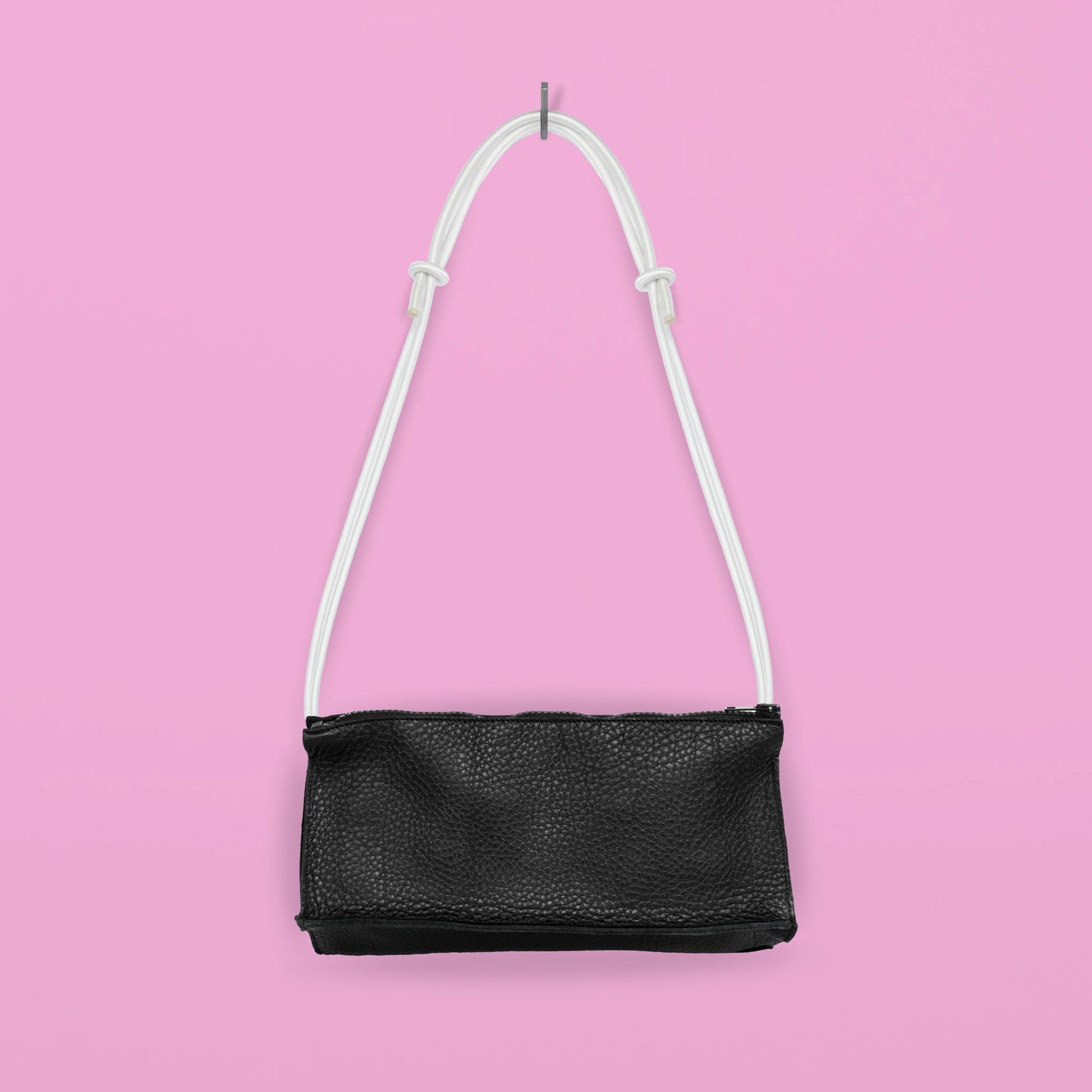 Daz Studion käsintehty crossbody-laukku, joka on valmistettu mustasta aidosta nahasta. Valkoinen olkahihna on säädettävä ja elastinen.