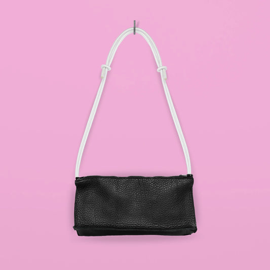 Daz Studion käsintehty crossbody-laukku, joka on valmistettu mustasta aidosta nahasta. Valkoinen olkahihna on säädettävä ja elastinen.